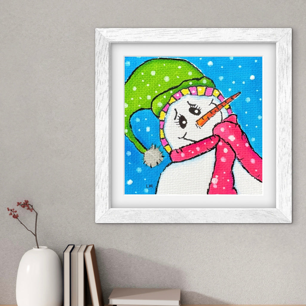 Framed picture of a snowman on a wall with decor items below.