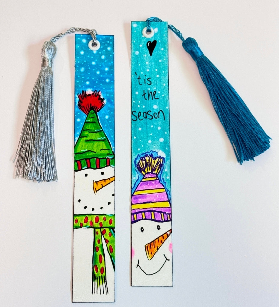 2 painted bookmarks with a snowman on each one. One saying 'Tis the Season' with a teal blue tassel
