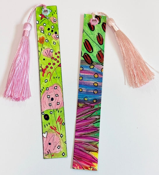 Two colorful hand-painted bookmarks with pink tassels, displayed on a plain white background.