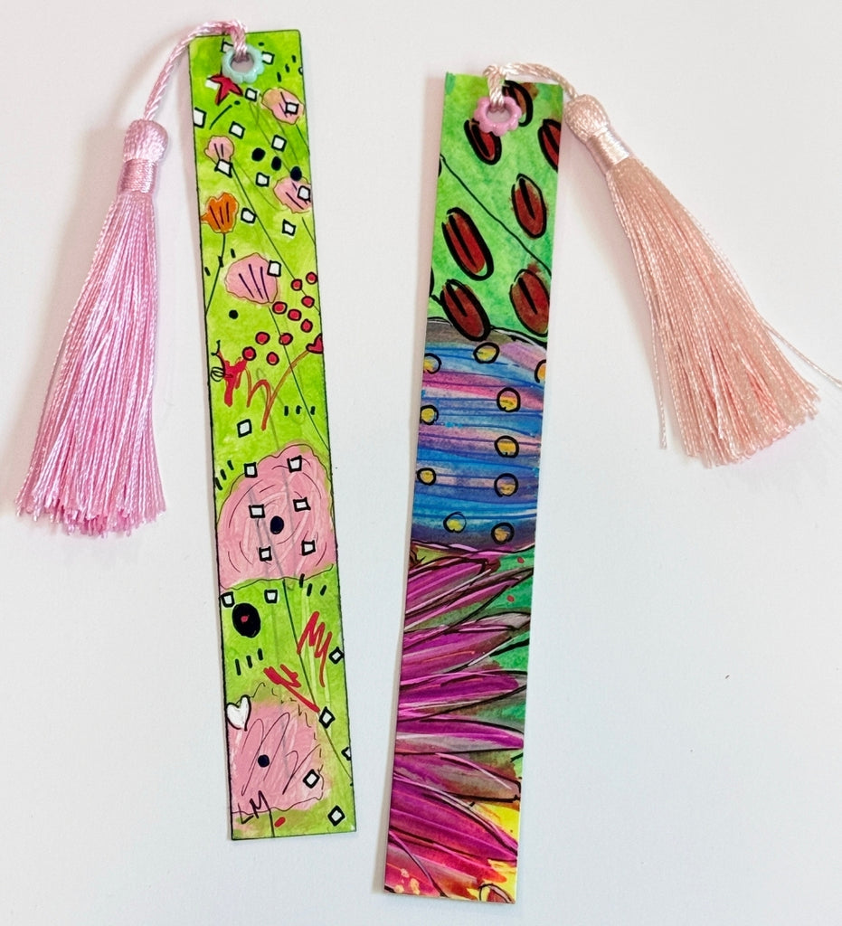 Two colorful hand-painted bookmarks with pink tassels, displayed on a plain white background.