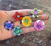 a hand holding 6 painted magnets in flower theme