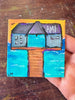 small painting with a pier and text 'AMI' with water and a sunset sky being held by a hand
