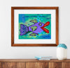 Framed children's drawing of a colorful fish on a wall above a wooden shelf.