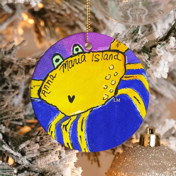 Round Christmas ornament with a yellow crab on a purple circle, hanging on a tree. Text says 'Anna Maria Island'