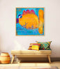 A framed abstract painting featuring a large orange and yellow fish on a blue background with the handwritten text 'Don't talk to the fish' in blue. The framed print is displayed on a light beige wall above a wooden bench with colorful patterned pillows.