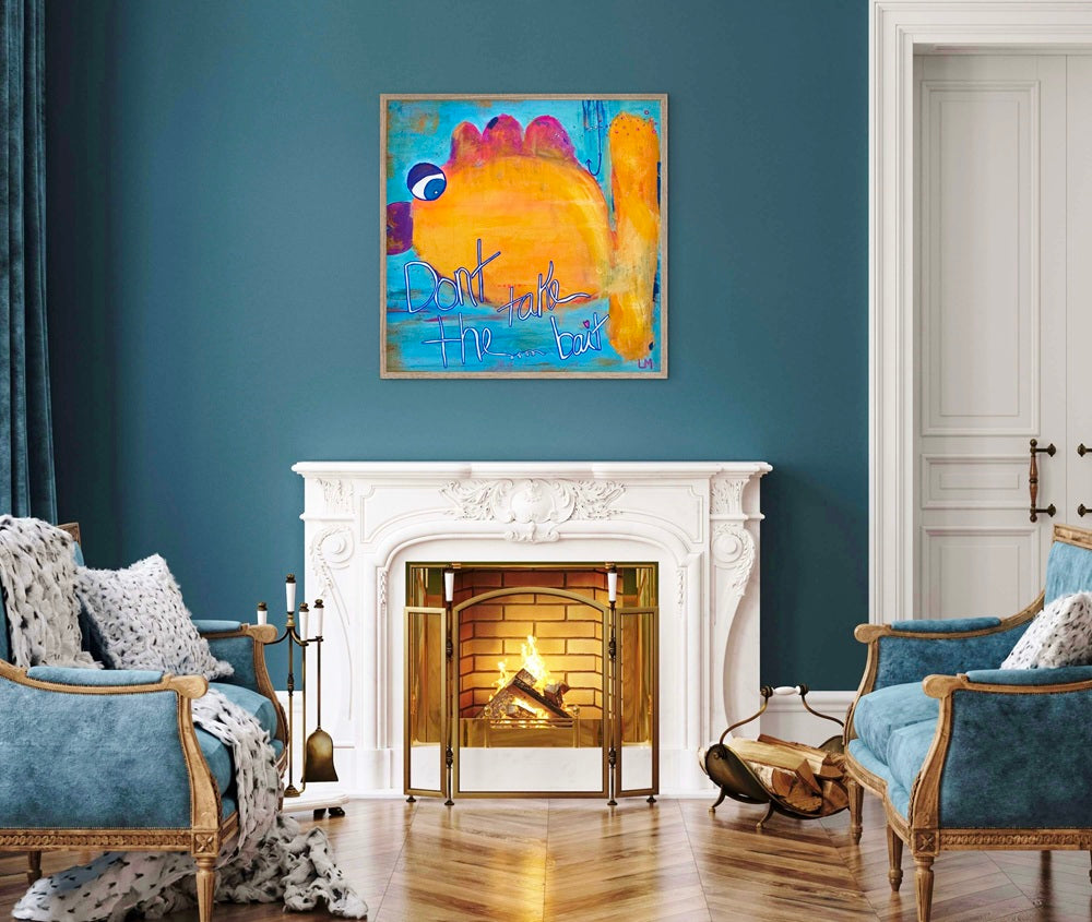 A colorful abstract painting featuring a large yellow and orange shape with blue, purple, and red accents, displayed in a silver frame on a dark teal wall above a white fireplace in a styled living room.