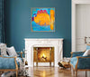 A colorful abstract painting featuring a large yellow and orange shape with blue, purple, and red accents, displayed in a silver frame on a dark teal wall above a white fireplace in a styled living room.