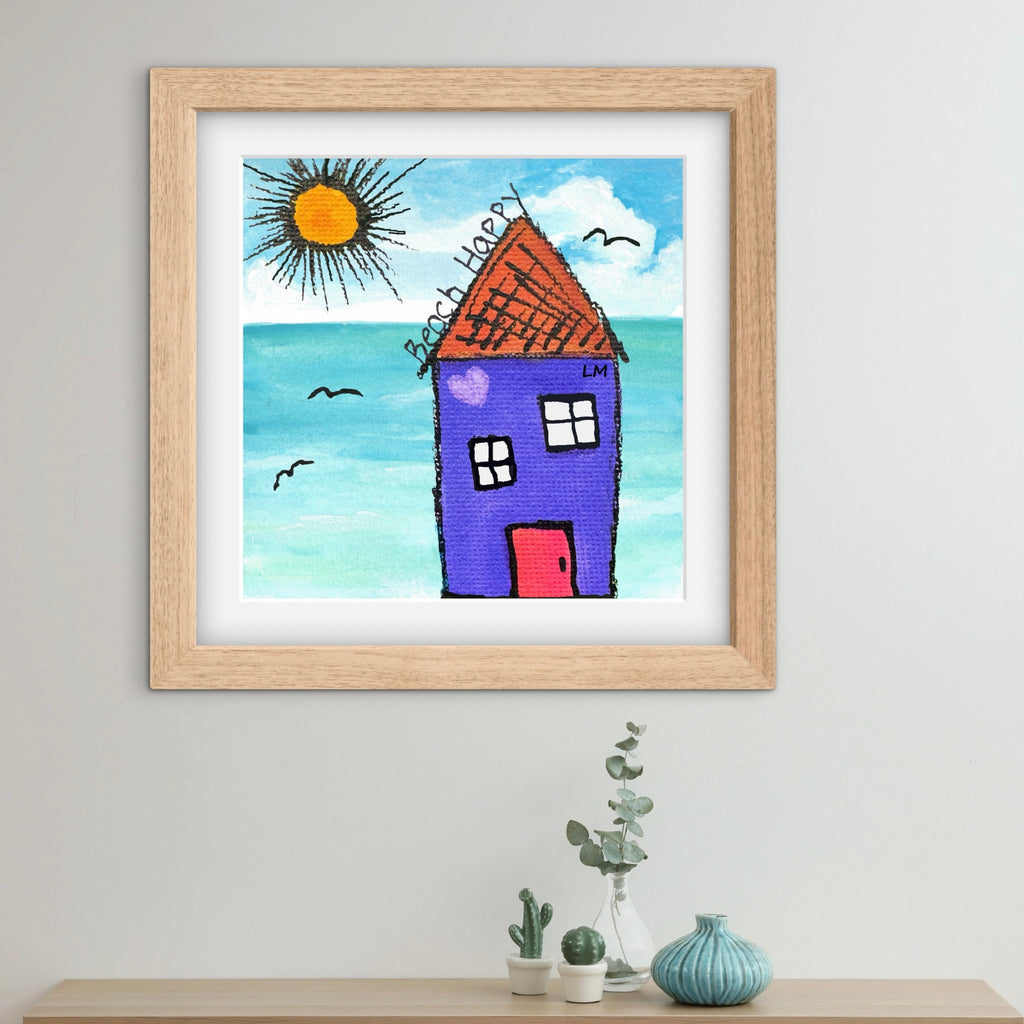 Framed art of a house with a sun and sea on a wall above a shelf.