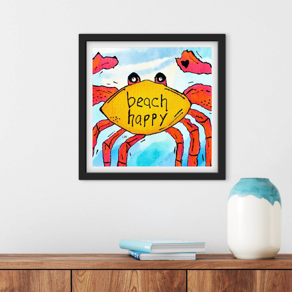 Framed artwork of a colorful crab with 'beach happy' text on a wall above a wooden shelf.