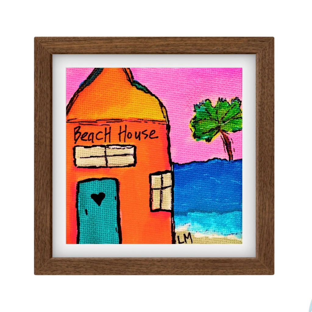 Framed artwork of a beach house with a palm tree and ocean.