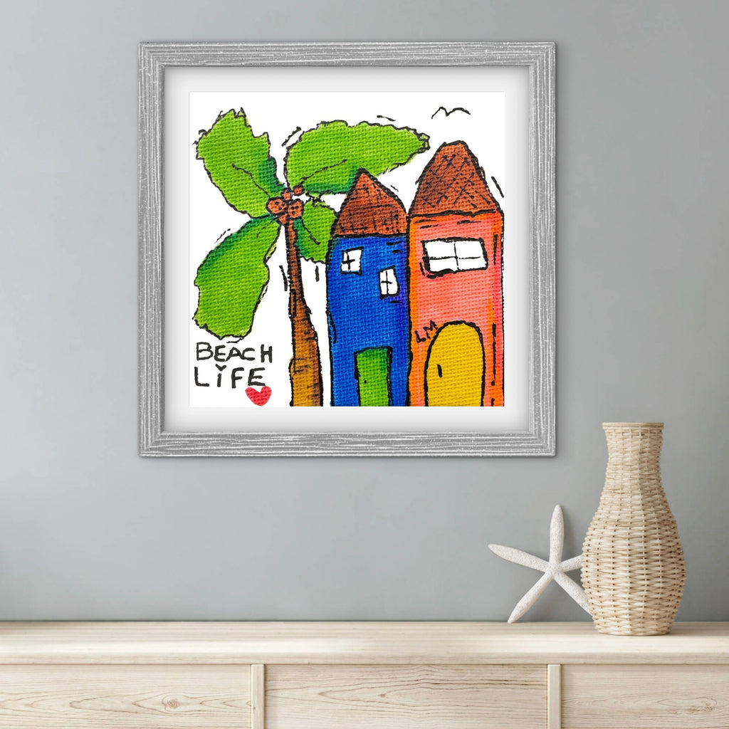 Framed artwork with colorful houses and a palm tree on a gray wall.