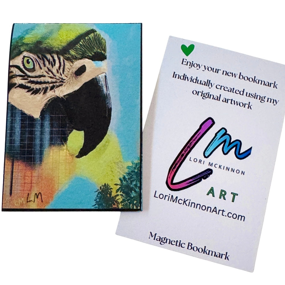 painted artwork showing a parrot head in bright blue, green, yellow, black, and beige tones, displayed next to a white card printed with the artist's name Lori McKinnon and the text 'Magnetic Bookmark.'.