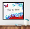 Framed artwork with a butterfly and 'Follow your dreams' text on a white wall above a wooden shelf.