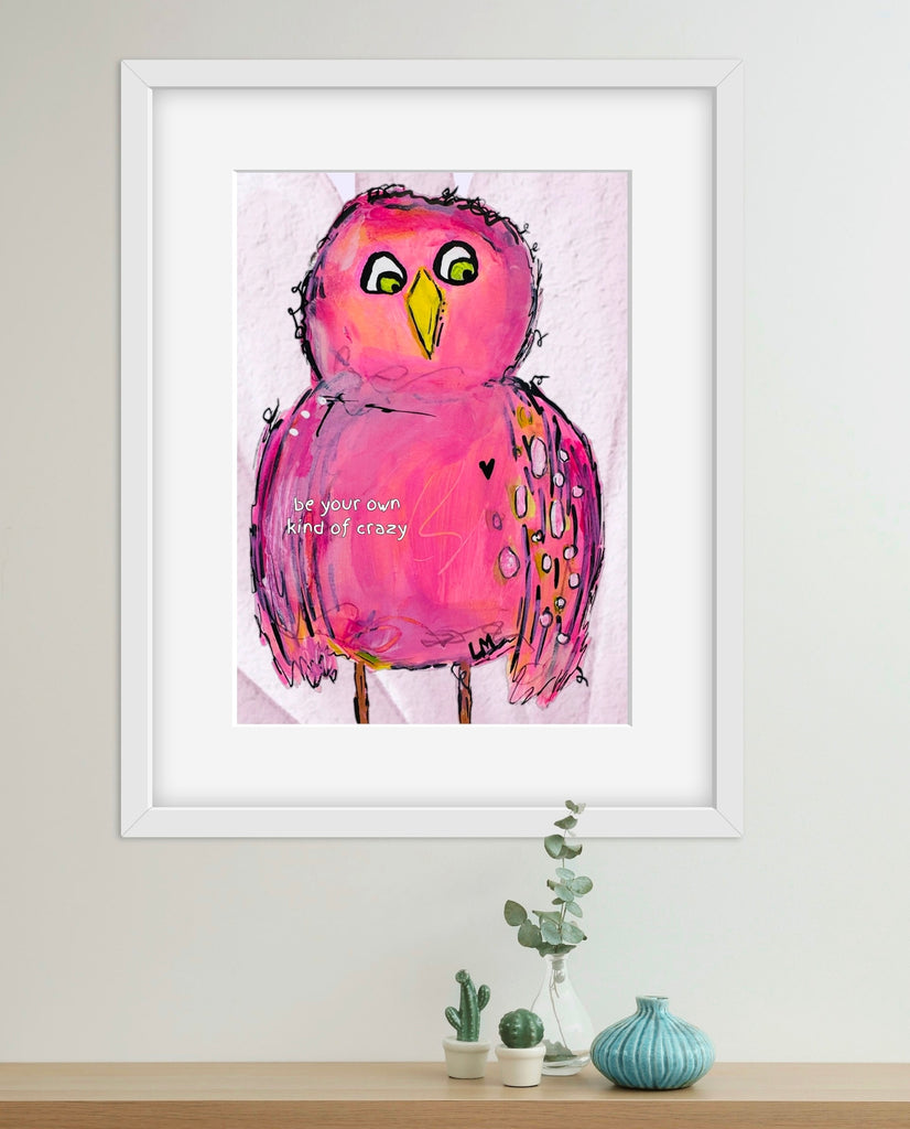 Framed artwork of a pink bird on a wall with decorative plants below.