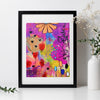 Framed colorful abstract art piece on a white wall with a vase and plant.