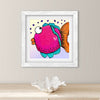 Framed artwork of a colorful fish on a wall above a wooden surface with a shell.