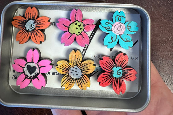 set of 6 flower magnets in various colors in a box being helf by a hand