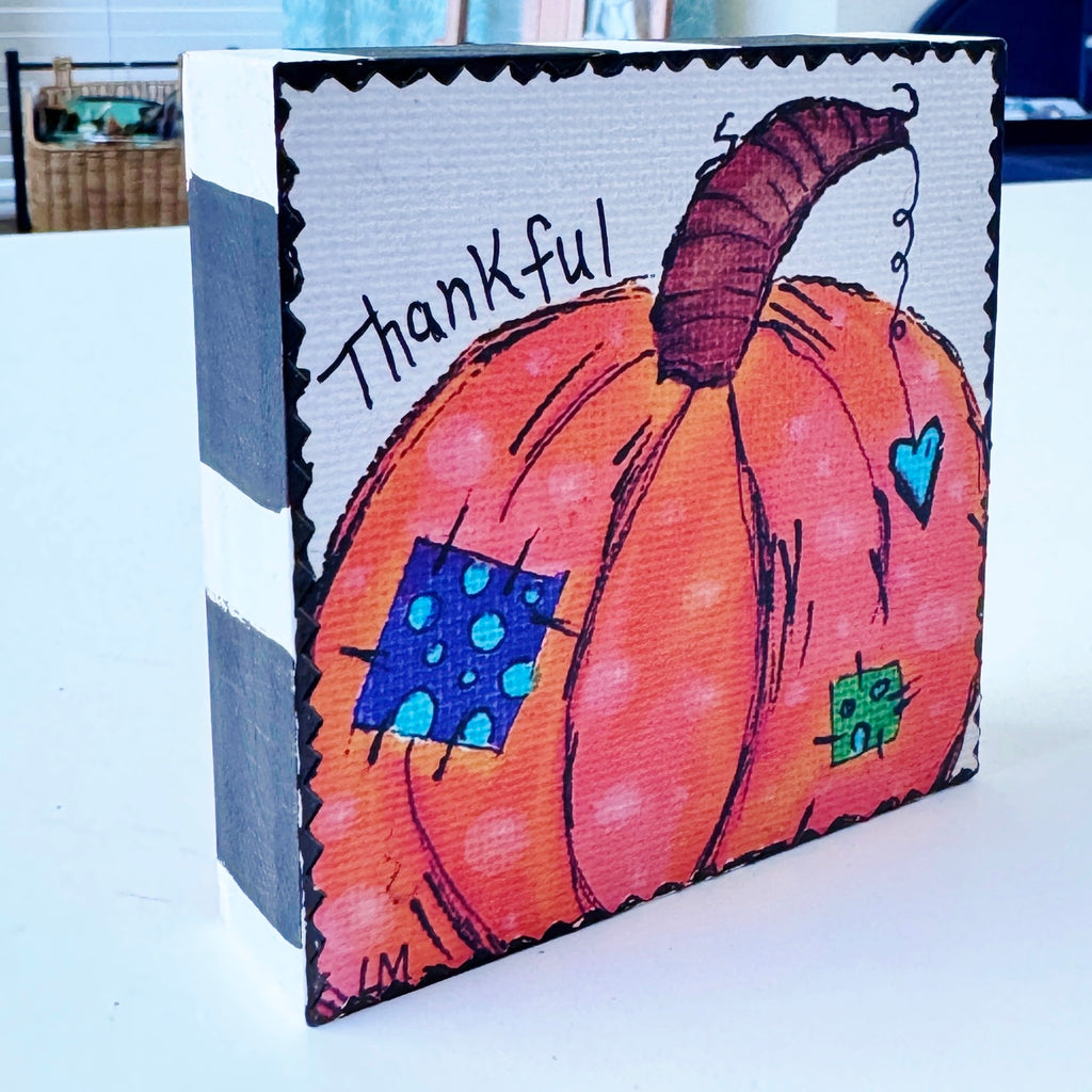 whimsical pumpkin painting on a wood block and the text 'thankful', The sides are painted with black and white stripes