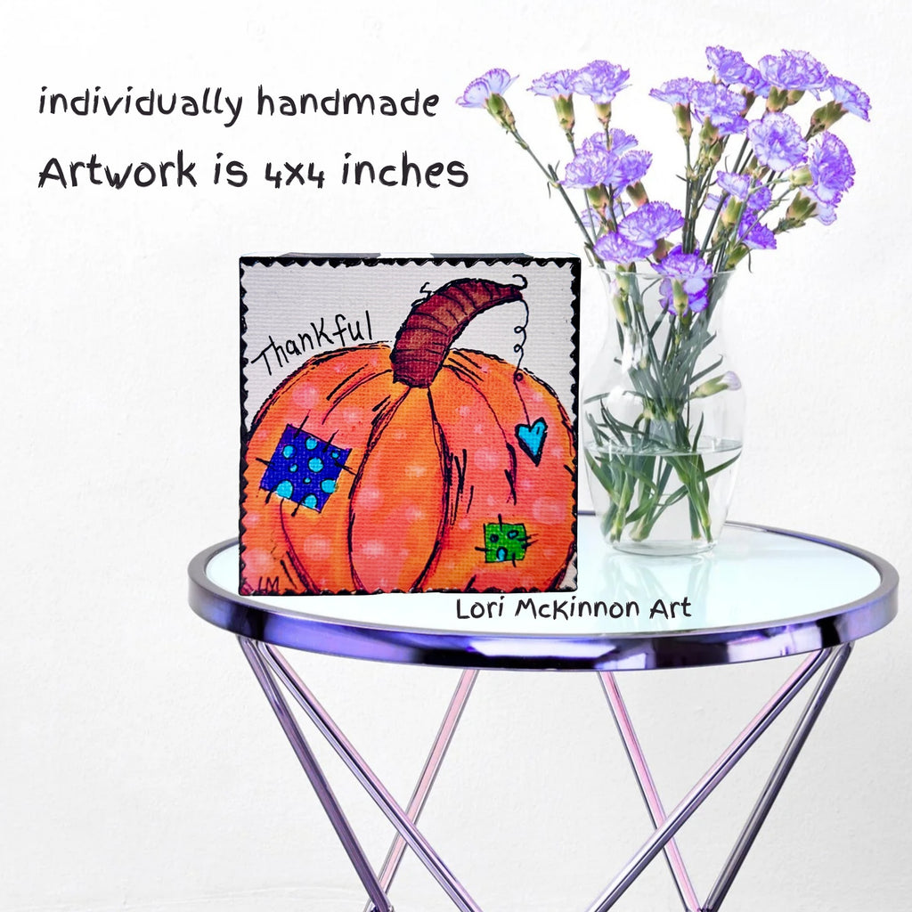 pumpkin artwork on a mall table next to a vase with purple flowers. text on image says it is '4x4 inches and individually handmade'