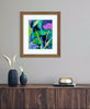 Colorful tropical painting with leaves, branches and a bird displayed in a wood frame with a white mat above a console table