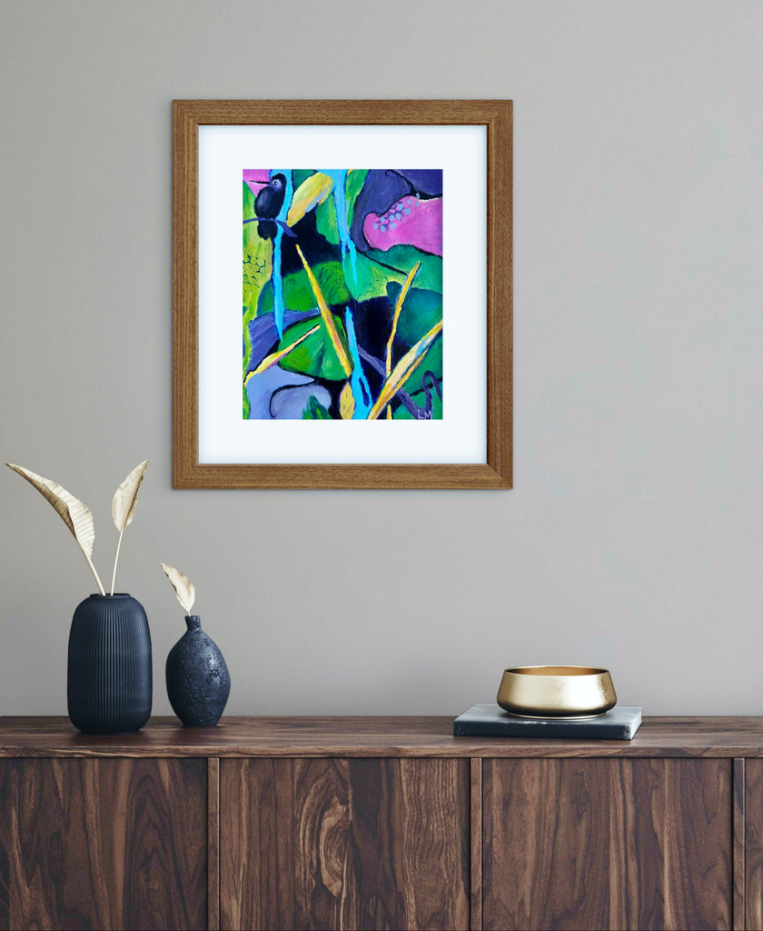 Colorful tropical painting with leaves, branches and a bird displayed in a wood frame with a white mat above a console table