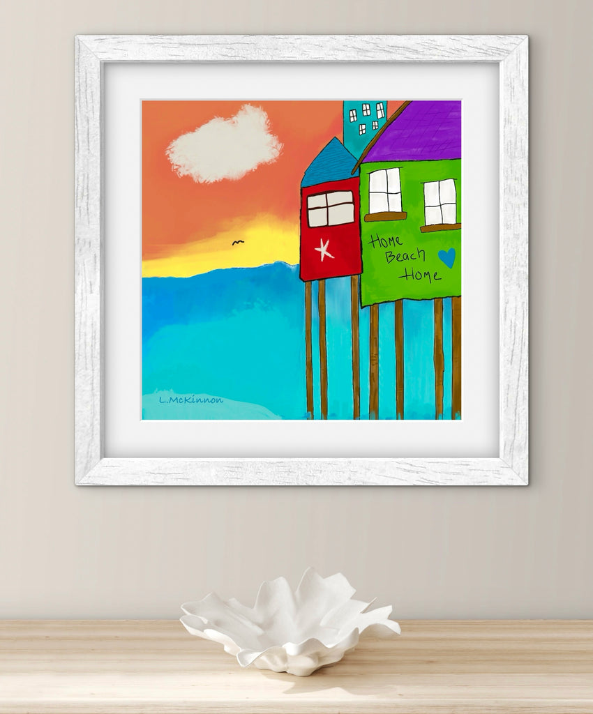 beach house artwork in white frame on a wall with shell bowl underneath