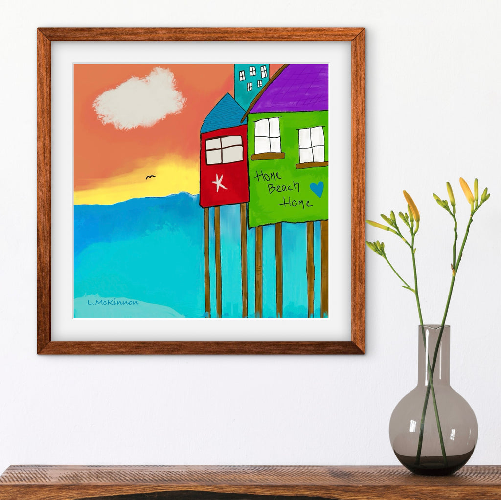 colorful beach home artwork in brown frame on white wall with vase of flowers below