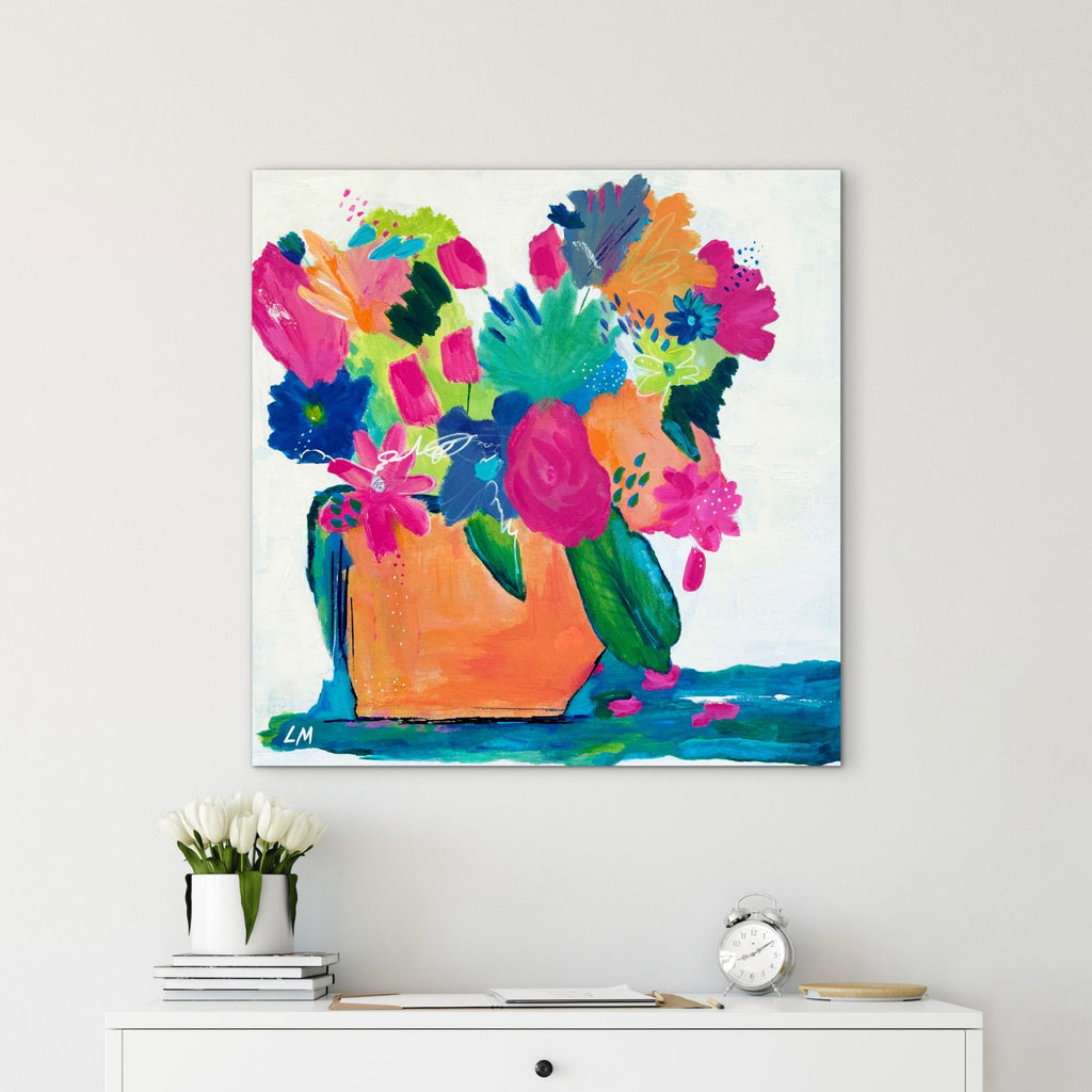 Colorful abstract painting of flowers on a white wall above a white cabinet.