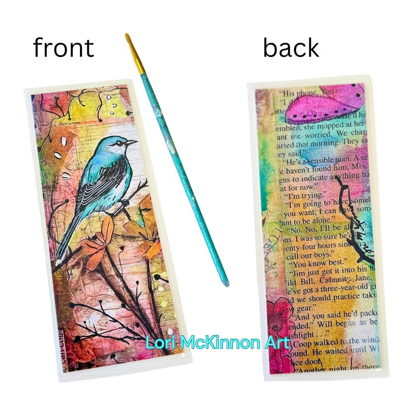 Artistic bookmark with a bird design on the front and text on the back, with a paintbrush for scale.