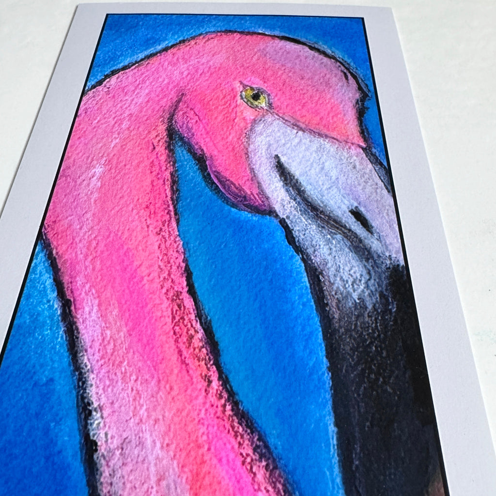 Angled close-up of the unframed “Pride” art print, showing the pink flamingo’s head, yellow eye, and black-and-white beak against a bright blue background.