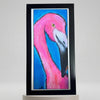 “Pride” art print featuring a pink flamingo against a bright blue background, displayed upright in a black frame.