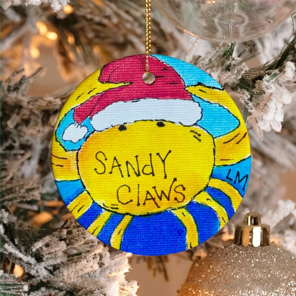 Christmas ornament with a crab wearing a red Santa hat, and 'Sandy Claws' text on a blue background, hanging on a tree.