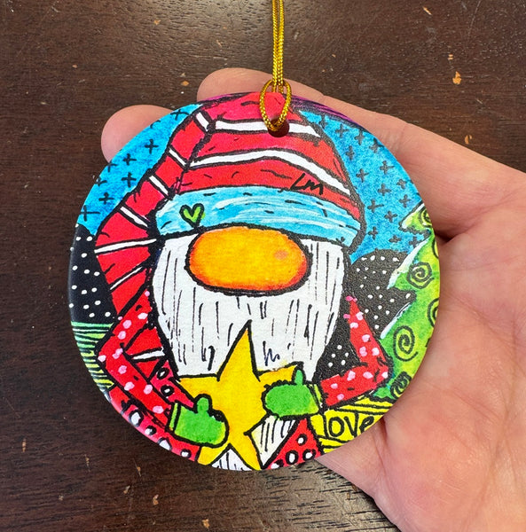 Colorful Santa Christmas ornament held by a hand on a wooden surface