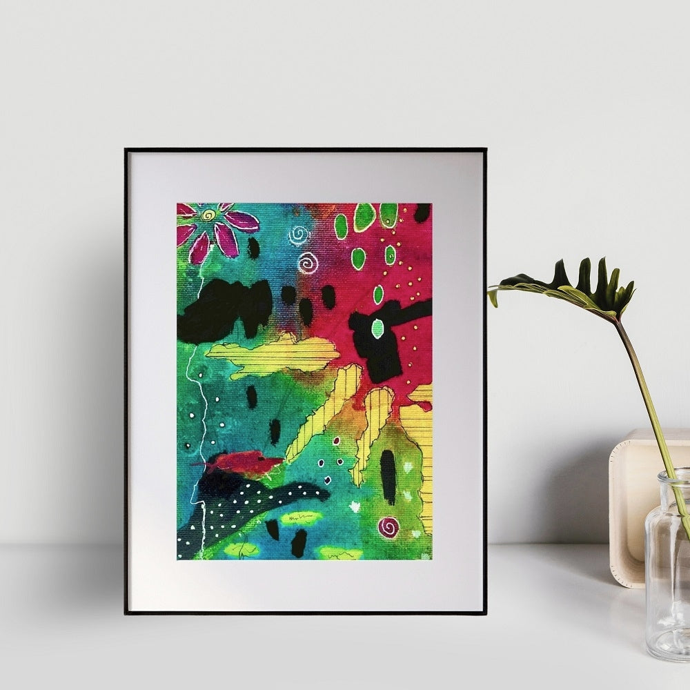 colorful abstract painting in a frame with a white mat sitting against a wall next to a plant on a table