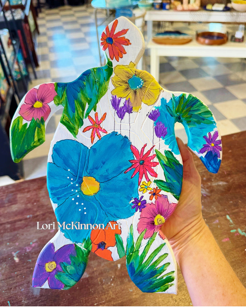 Colorful turtle-shaped art piece with floral patterns held by a hand.