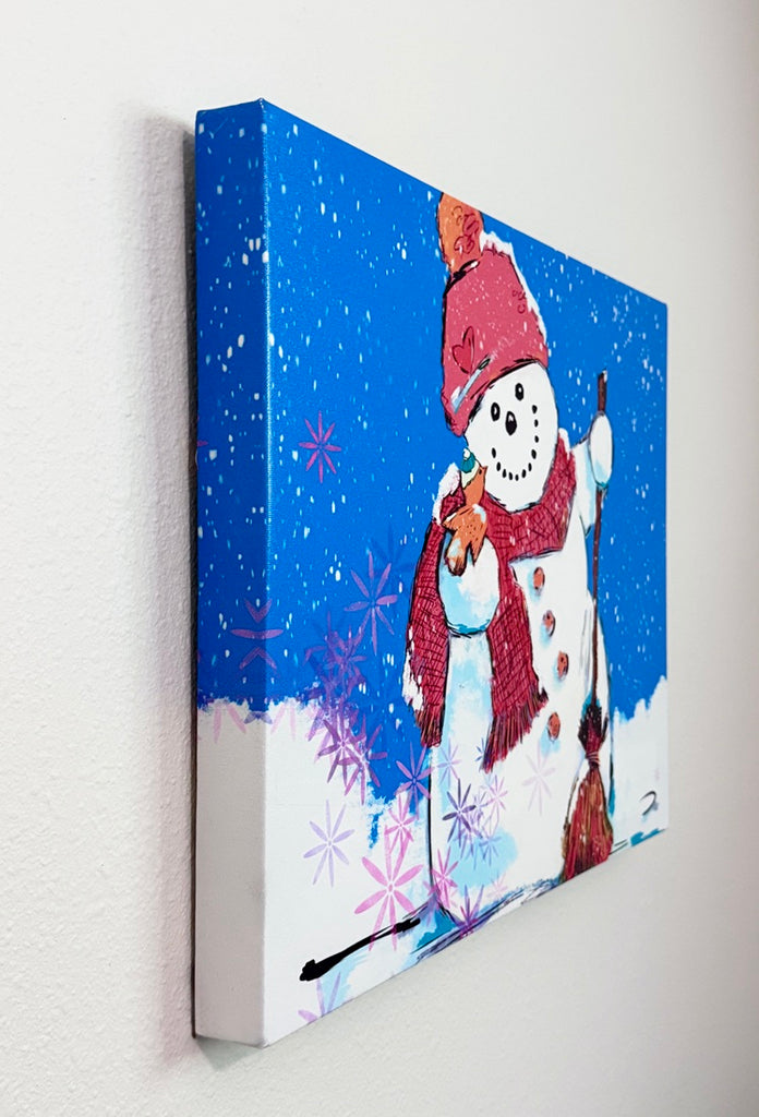 A canvas print featuring a whimsical painted snowman on a bright blue snowy background, hanging on a white textured wall.