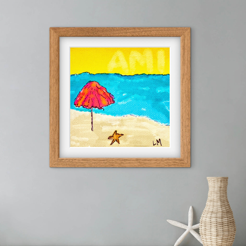 Framed artwork of a beach scene with an umbrella, sand, and starfish on a gray wall.