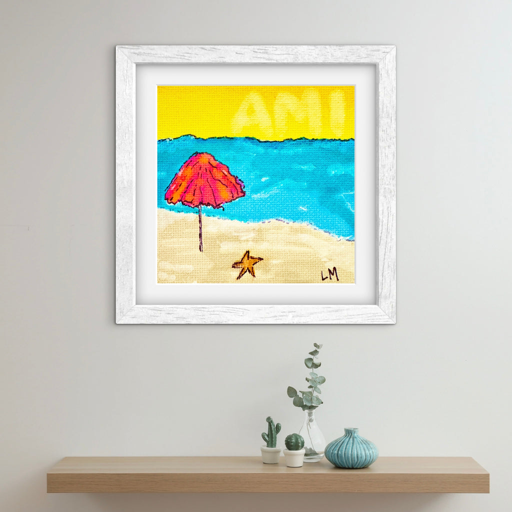 Framed artwork of a beach scene with a pink umbrella and starfish on a white wall.