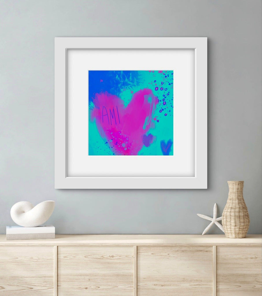 Framed abstract art with pink and blue hearts on a gray wall above a wooden cabinet.