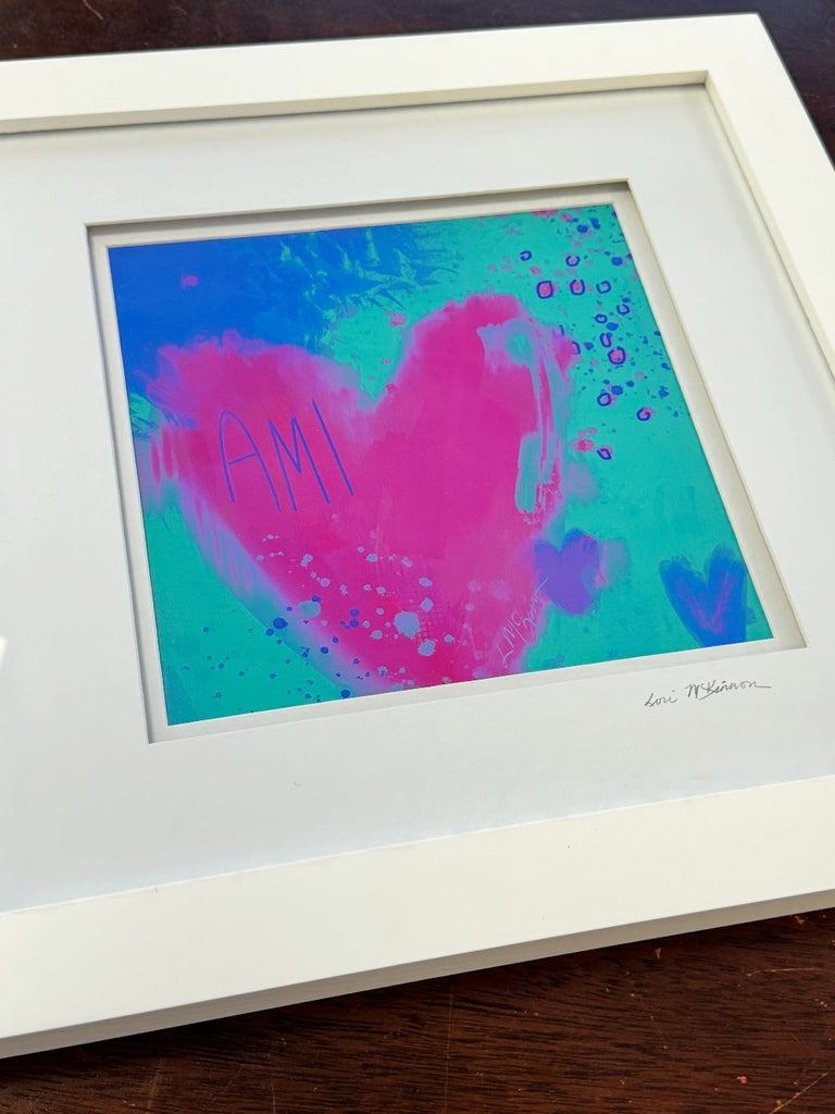 Framed abstract artwork with pink and blue colors on a wooden surface