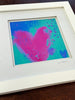 Framed abstract artwork with pink and blue colors on a wooden surface