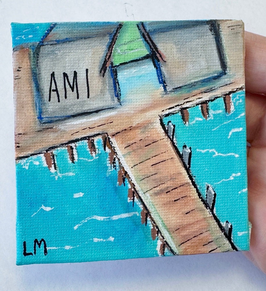A colorful painting with "AMI" text and artist's initials. Painting is of a building on a pier with a water background