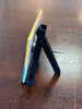 Small black stand holding a yellow and blue object on a wooden surface
