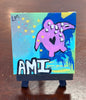 Small abstract painting with a turtle and 'AMI' text displayed on a small easel