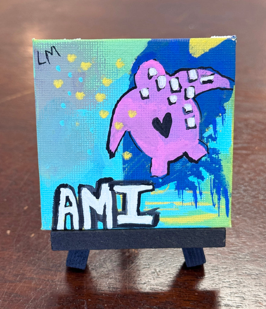 Small abstract painting with a turtle and 'AMI' text displayed on a small easel