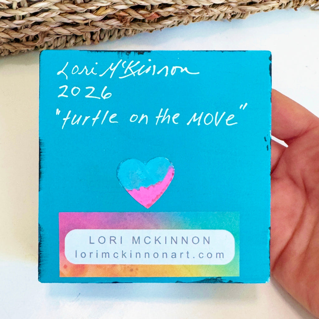 wood block painted blue with artist signature, website address, year and the name of the artwork along with a small heart