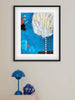 Framed abstract artwork on a wall with a blue lamp and decorative item below.