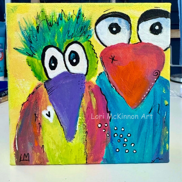 Colorful painting of two whimsical birds with a yellow background, signed 'Lori McKinnon Art'.