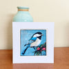Bird and Berries original acrylic painting by Lori McKinnon, showing a blue, black and white bird beside red berries, displayed in a white mat