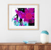 Framed abstract artwork with flowers and the word 'Bloom' on a wall above a wooden shelf.